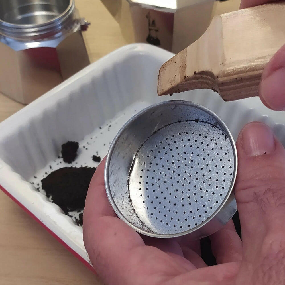 Il porta caffè pulito dal caffè esausto grazie all'uso dell'aprimoka, sullo sfondo si vede la Caffettiera Bialetti Moka Express 3 tazze svitata grazie all'aprimoka