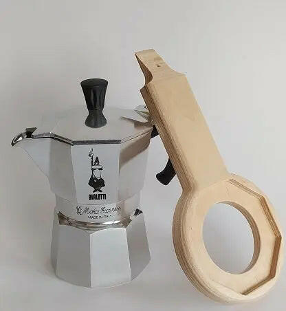 Caffettiera Bialetti Moka Express a tre tazze sulla quale è appoggiato sulla destra l'aprimoka in legno che consente la più facile apertura della caffettiera, il facile riempimento del porta caffè e l'immediata rimozione del caffè vecchio
